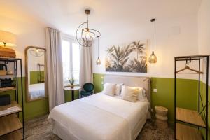 um quarto com uma cama branca e paredes verdes em Hôtel Barnea em Biarritz