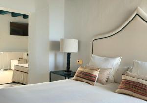a bedroom with a white bed with pillows and a lamp at Canalejas 3 Vejer in Vejer de la Frontera
