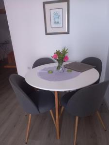 un tavolo bianco con sedie e un vaso di fiori di Dani a Zara (Zadar)