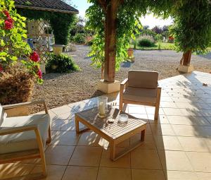 eine Terrasse mit einem Tisch, 2 Stühlen und einem Laptop in der Unterkunft Chambre d'hôtes de charme, A Nosté M&P in Poussignac