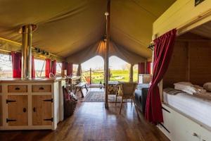 a room with a tent with a bed and a table at Safari Tent 5 With Log Burning Tub At Tapnell Farm in Yarmouth