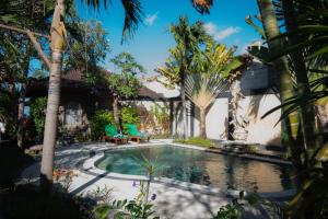 a swimming pool in a yard with palm trees at Bungalow Geringsing in Candidasa