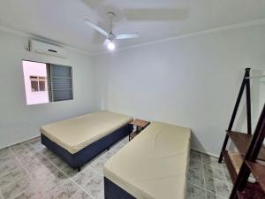 1 dormitorio con 2 camas y ventilador de techo en 01 dorm c/ar cond, wi-fi, 1 vaga, praia da Enseada, próx ao Pão de Açúcar en Guarujá