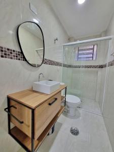 y baño con lavabo, espejo y aseo. en 01 dorm c/ar cond, wi-fi, 1 vaga, praia da Enseada, próx ao Pão de Açúcar en Guarujá