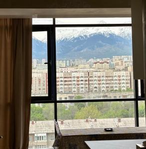a view of a mountain from a window at Стильная квартира в Алматы in Almaty