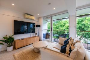 a living room with a couch and a flat screen tv at Riverside studio apartment with parking and view in Brisbane
