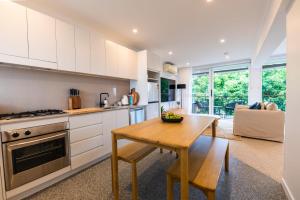 a kitchen with white cabinets and a wooden table at Riverside studio apartment with parking and view in Brisbane