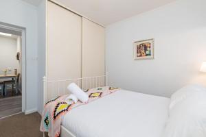 Dormitorio blanco con cama y mesa en Convenient and Cosy 1BD Unit with free wine, en Wayville