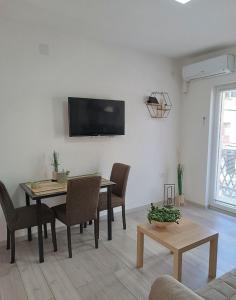 uma sala de estar com uma mesa e uma televisão na parede em Sunčani apartman 1 em Krupanj