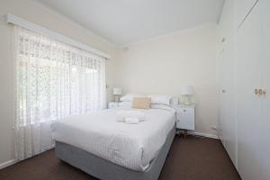 a white bedroom with a bed and a window at Vintage Charm in Vale Park in Broadview