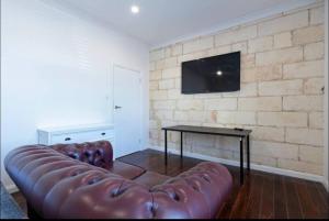 a living room with a leather couch and a table at Lovely Beachside Largs Bay unit - free wine in Largs