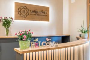 - une salle d'attente avec des fleurs et un panneau de bienvenue dans l'établissement Landjuwel Ferienwohnungen, à Herbertingen