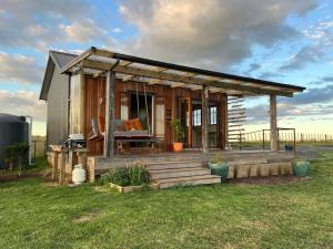 a tiny house with a porch and a deck at Romantic hilltop hideaway - Skyview Cottage in Dairy Flat