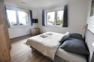 a bedroom with a large bed and two windows at Wellness Villa Bobrik in Pribylina