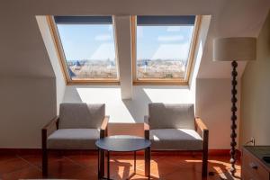 two chairs and a table in a room with two windows at Puerto Antilla Grand Hotel in Islantilla