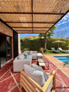 une terrasse avec des canapés, une table et une piscine dans l'établissement Villa Sofia - Golf Amelkis Marrakech, à Marrakech