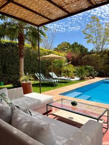 un soggiorno con divano e una piscina di Villa Sofia - Golf Amelkis Marrakech a Marrakech
