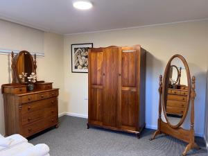 サンディ・ベイにあるMagnolia Houseのベッドルーム(木製ドレッサー、鏡付)