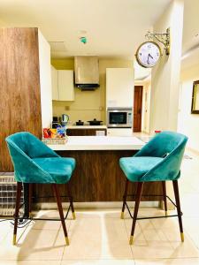 two chairs in a kitchen with a clock on the wall at Mirhaa Homes # 1 -Gold Crest Mall One Bed Apartment By Dr - Subhan Shahid in Lahore