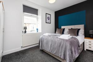 a bedroom with two beds and a blue accent wall at Stylish Three Bed House Burnley in Burnley