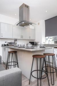 a kitchen with three bar stools and a counter at Stylish Three Bed House Burnley in Burnley