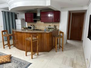uma cozinha com armários vermelhos e um balcão com bancos em Coquette appart de plage em Hammam Sousse