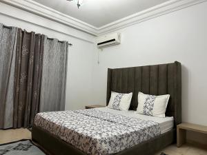- une chambre avec un lit doté d'une tête de lit grise dans l'établissement Coquette appart de plage, à Hammam Sousse
