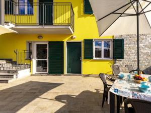 a yellow house with a table and an umbrella at Apartment Raggio di Sole Apartment A and B by Interhome in Consiglio di Rumo
