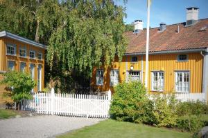 een geel huis met een wit hek ervoor bij Det Lille Hotel in Risør