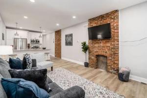 a living room with a brick fireplace and a tv at 2 homes side by side downtown with fenced yard and hot tub in Columbus