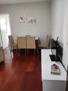 uma sala de estar com uma mesa e cadeiras e uma televisão em Apto com suíte, garagem, localização privilegiada em Belo Horizonte