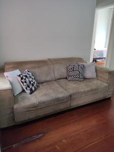 a brown couch with pillows on it in a living room at Apto com suíte, garagem, localização privilegiada in Belo Horizonte