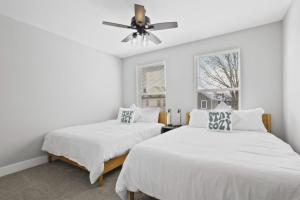 two beds in a white room with a ceiling fan at 2 homes side by side downtown with fenced yard and hot tub in Columbus