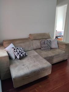 - un canapé brun avec des oreillers dans le salon dans l'établissement Apto com suíte, garagem, localização privilegiada, à Belo Horizonte