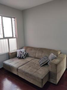 a brown couch in a living room with pillows on it at Apto com suíte, garagem, localização privilegiada in Belo Horizonte