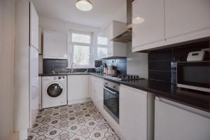 a kitchen with white cabinets and a washer and dryer at Modern And Vibrantly Designed Apartment in Motherwell