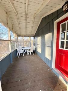 a porch with two chairs and a table with a red door at Cottage 6- Lees Ford Marina in Nancy