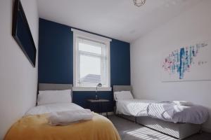 a bedroom with two beds and a window at Modern And Vibrantly Designed Apartment in Motherwell