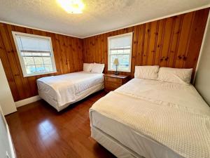 two beds in a bedroom with wooden walls and wooden floors at Cottage 6- Lees Ford Marina in Nancy
