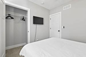 コロンバスにあるMassive home downtown with Hot Tubの白いベッドルーム(ベッド1台、薄型テレビ付)