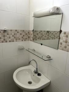 een badkamer met een wastafel en een spiegel bij Chambre spacieuse avec balcon - salle de bain extérieure privée & breakfast in Saint-Louis