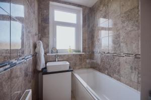 bagno con vasca, lavandino e finestra di Modern And Vibrantly Designed Apartment a Motherwell