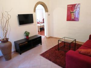 a living room with a tv and a red couch at appartamento Papaveri di Casa Mosaico in Volterra