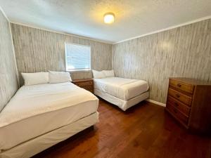 a bedroom with two beds and a dresser and a window at Cottage 12 Lees Ford Marina in Nancy