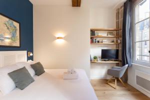 a bedroom with a white bed and a desk at Le Kodama - Appt en plein coeur de St Malo in Saint Malo