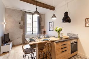 a kitchen with a large wooden island with chairs at Le Kodama - Appt en plein coeur de St Malo in Saint Malo