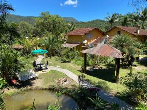 ein Haus mit einem Teich davor in der Unterkunft Pousada Jardim Secreto in Teresópolis