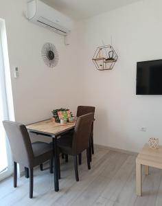 a dining room table with chairs and a television at Sunčani apartman 2 in Krupanj