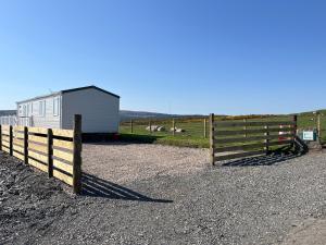 a fence next to a barn and a building at Robyn’s Nest in Lybster
