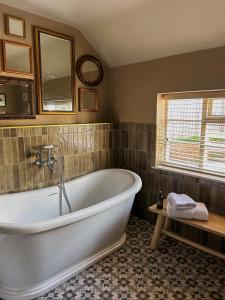 uma casa de banho com uma banheira e uma janela em The Fitz Farmhouse em Swynnerton